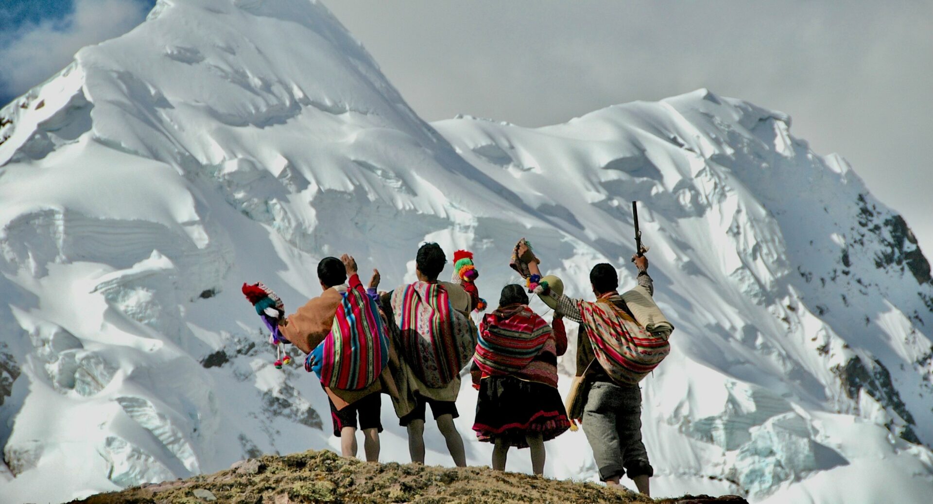 Four people looking at snow-covered mountaintops.