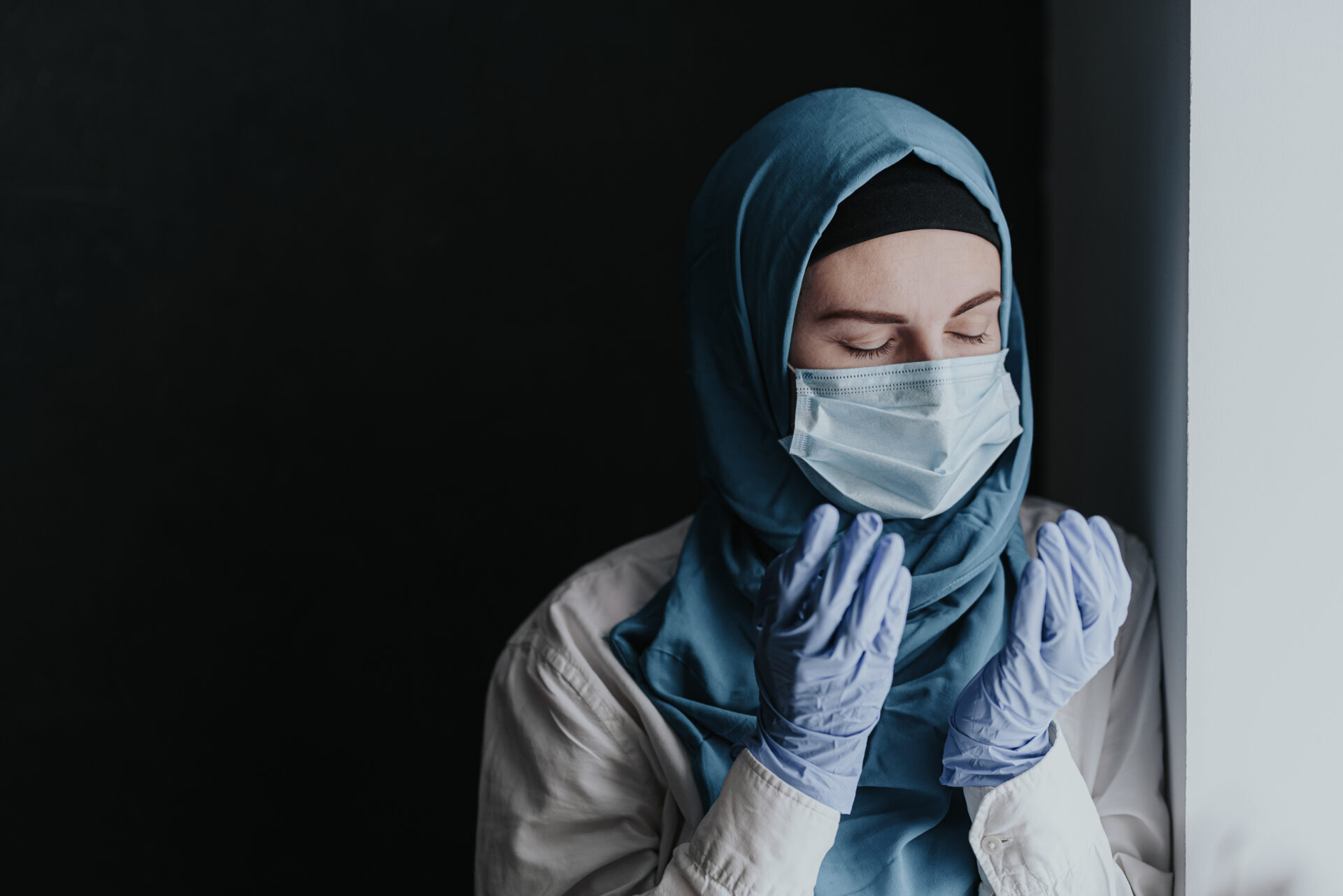 Tired medical worker doctor, muslim woman in hijab praying after taking a large number of patients due to epidemic of coronavirus