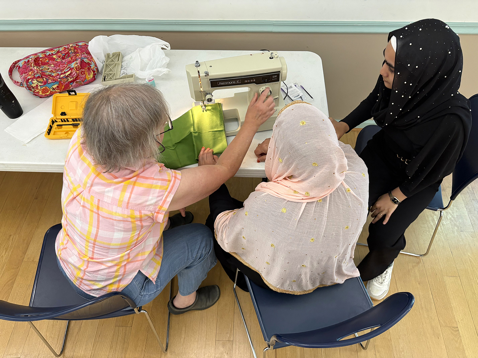 Maureen Kurtz, left, works with interpreter Sama Qazikhani, 17, right, to instruct a participant in the Stitching for Hope sewing circle at the Eno River Unitarian Universalist Fellowship in Durham, N.C. (RNS photo/Yonat Shimron)